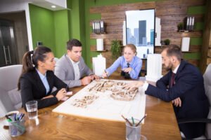 Business professionals discussing architectural plans in a meeting room, focused on identifying profitable housing schemes in Lahore.