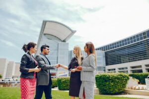 Business professionals shaking hands in front of Blue World City building, symbolizing partnership in real estate investment.